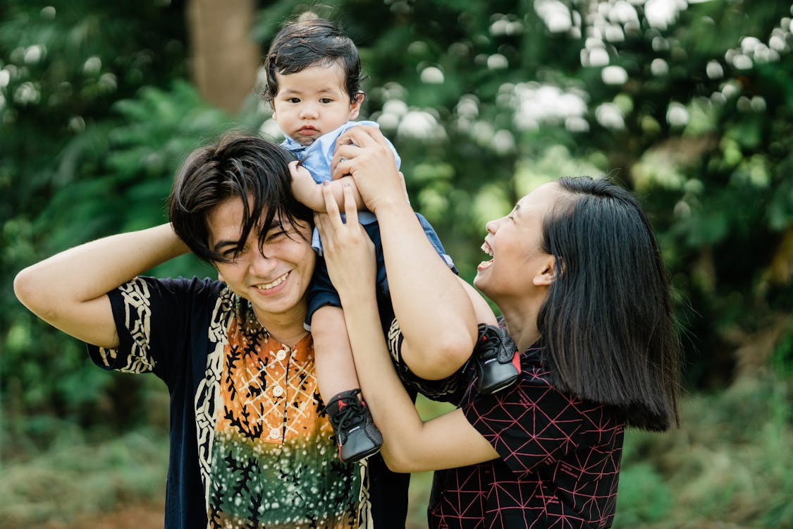 Young parents laughing with their baby outdoors, illustrating how affordable life insurance costs in Florida protect growing families